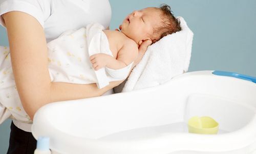 Sleepy baby enjoys first bath after birth